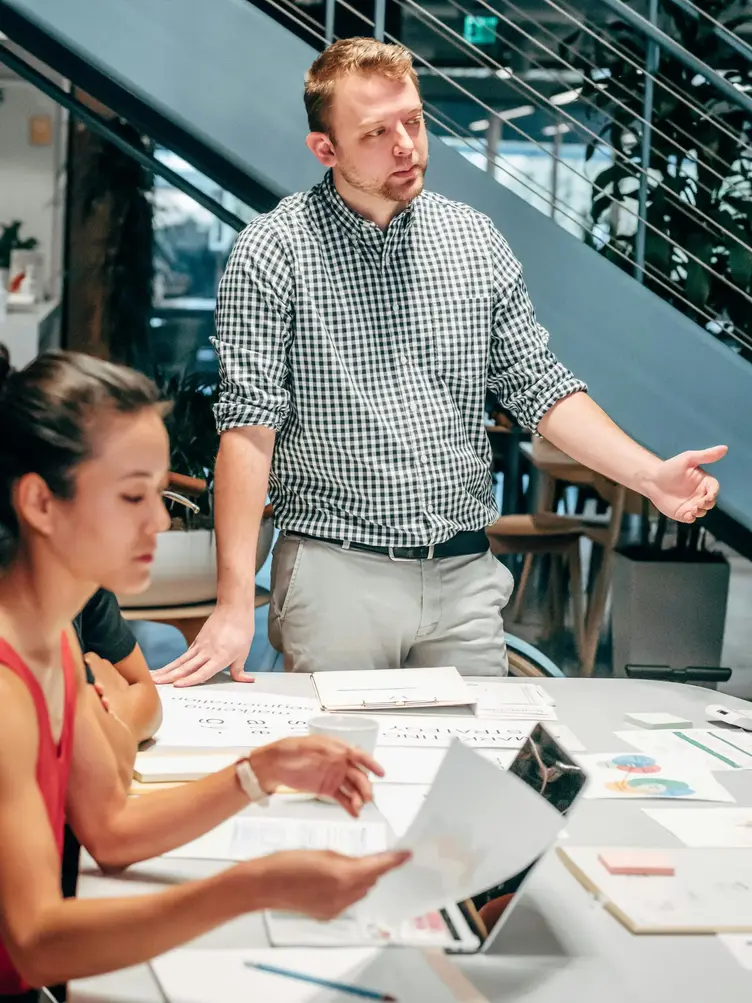 Coaching that leads to clarity and action Man leading a strategic discussion with team members in a modern workspace