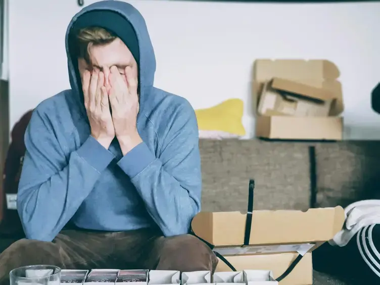 From overwhelm to transformation Man in hoodie sitting with face in hands, showing stress or emotional exhaustion