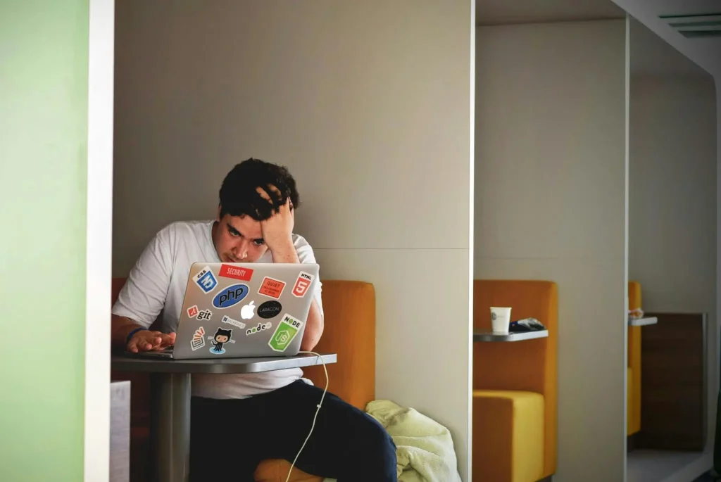 Stuck in overthinking and analysis paralysis Frustrated man holding his head while looking at laptop alone